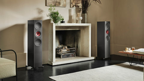 A pair of black floorstanding speakers either side of a fireplace in a living room
